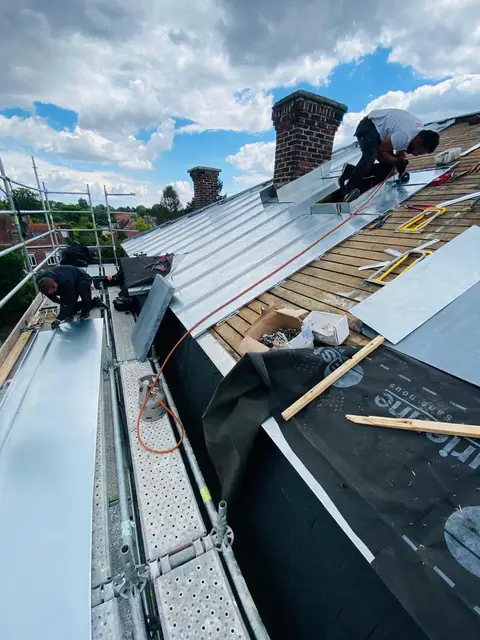Couvreurs posant du zinc à joint debout sur écran de sous-toiture depuis un échafaudage, métropole lilloise