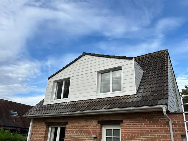 Bardage composite blanc posé sur le chien-assis d'une maison en briques, métropole lilloise
